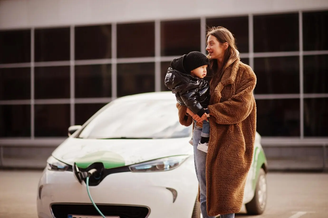 A young mother and her child charging an electric car at the electric gas station.