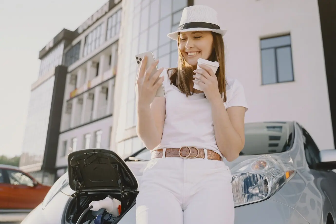 A woman charging an electric car at an electric charging station.